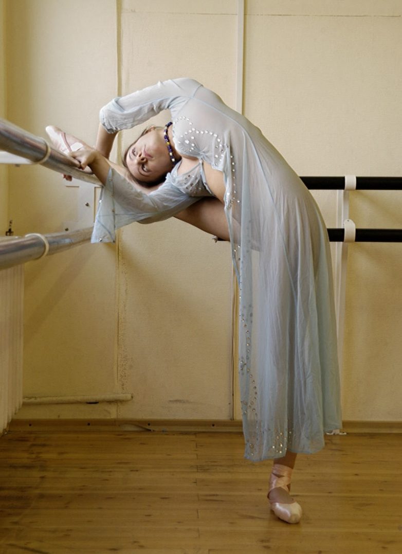 Голая балерина тренируется у станка