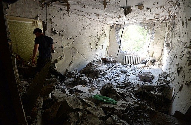 Мужчина в своей квартире в одном из домов Донецка, разрушенного в результате обстрела, 13 августа 2014 года. Фото: Михаил Воскресенский / РИА Новости