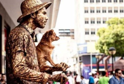 Собачка, которая помогает своему хозяину, уличному артисту, изображать живую статую